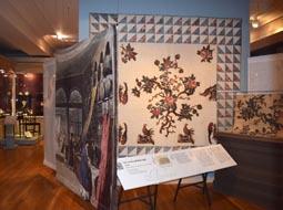 Banners positioned at angles protect quilts and add visual flair. Low object labels in large type provide accessibility for all visitors.