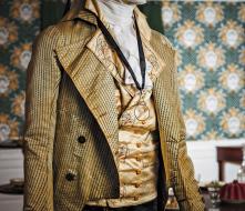 Green striped silk coat over a silk satin embroidered waistcoat believed to be the wedding waistcoat of Thomas Rumrill in 1795. The brass monocle or “quizzing glass” was possibly owned by Major Joseph Savage.